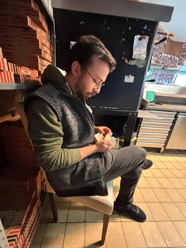 Ein Mann mit Brille sitzt neben den Pizzakartons im Restaurant