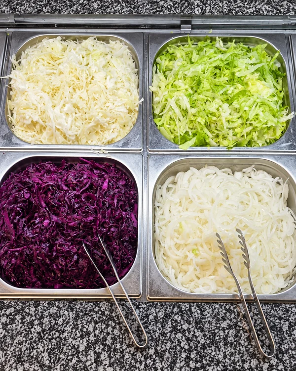 Weißkohl, Eisbergsalat, Rotkohl und geschnittene Zwiebeln in der Haci Baba Salattheke